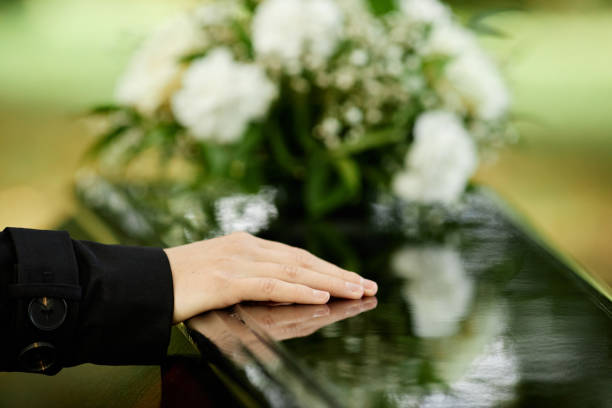 Close up of female hand on coffin saying goodbye at outdoor funeral ceremony, copy space